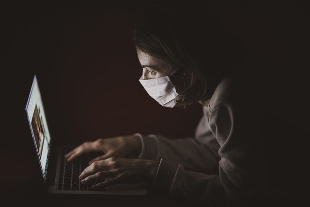 Ατομο που δουλεύει στον υπολογιστή με μασκα προστασιας
